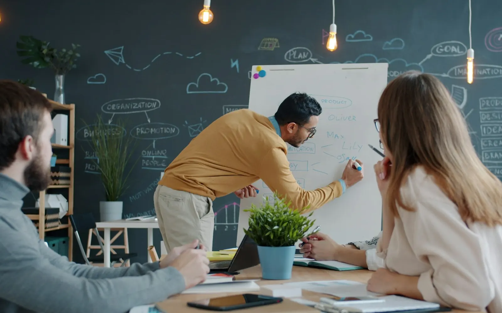 A team member presenting ideas on a whiteboard to colleagues